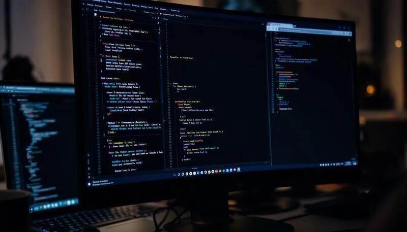Un écran d'ordinateur montre du code de programmation avec plusieurs fenêtres ouvertes, suggérant un environnement de travail dynamique pour un projet de reconversion professionnelle. Ce visuel évoque l'importance des compétences techniques dans le marché du travail moderne.