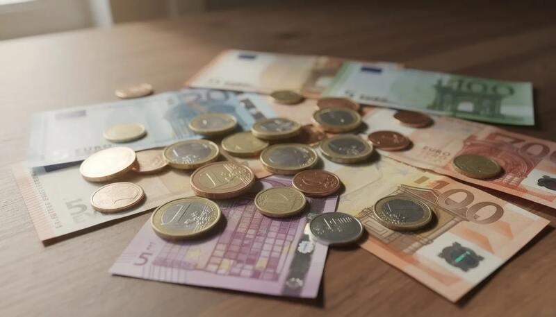 L'image montre des pièces et des billets en euros étalés sur une table, représentant la monnaie utilisée en France. Ces éléments évoquent le niveau de vie et les salaires, notamment le salaire moyen en France, influençant le pouvoir d'achat des salariés du secteur privé.