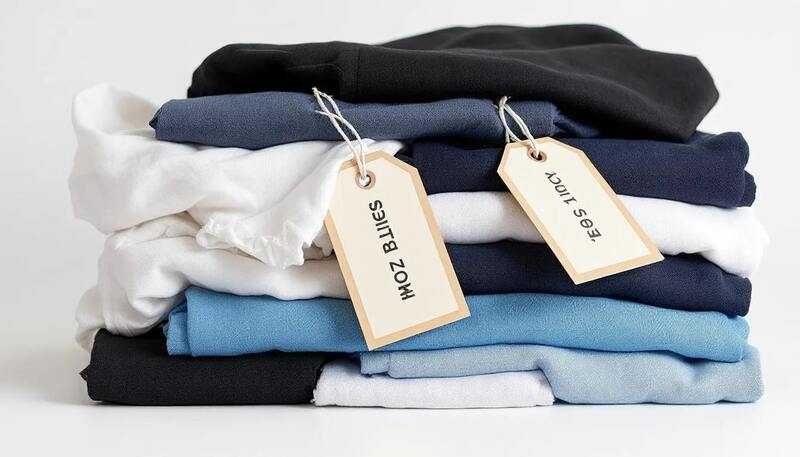 Une pile de vêtements soigneusement pliés est présentée, chacun portant une étiquette de prix, illustrant des articles qui pourraient aider à arrondir ses fins de mois. Cette image évoque l'idée de gérer son budget en trouvant des produits à prix abordables.